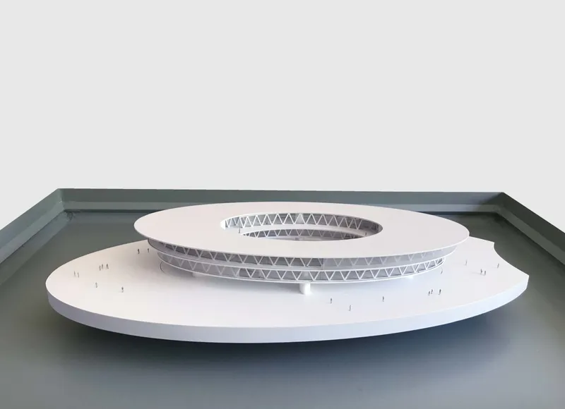 Physical model showing the tiered circular roof with exposed triangular truss ring around the central opening