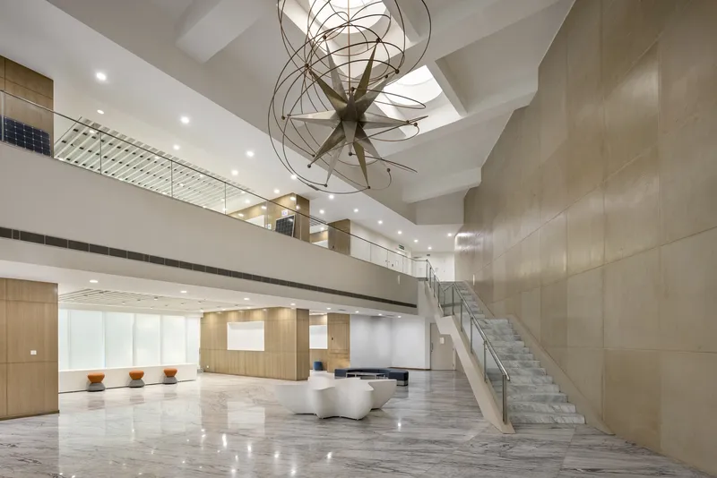 Double-height lobby with marble floors, curved skylight, suspended chandelier, and cantilevered mezzanine