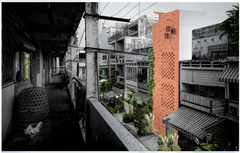 View from adjacent balcony showing the perforated brick tower rising above densely packed neighboring buildings with greenery