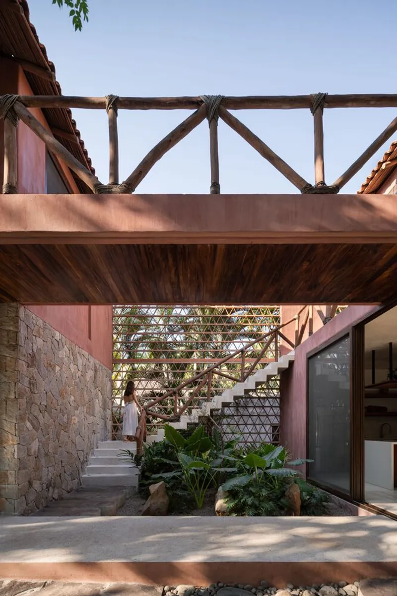 Courtyard view of the timber-framed bridge and open stair connecting upper and lower levels with planted beds below