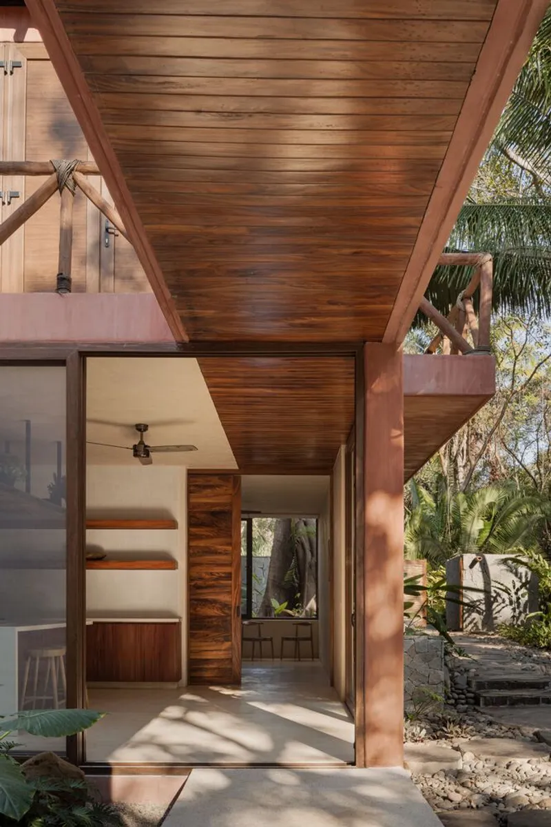 Entrance threshold showing wood-clad ceiling and walls with pink stucco column framing a view through the residence