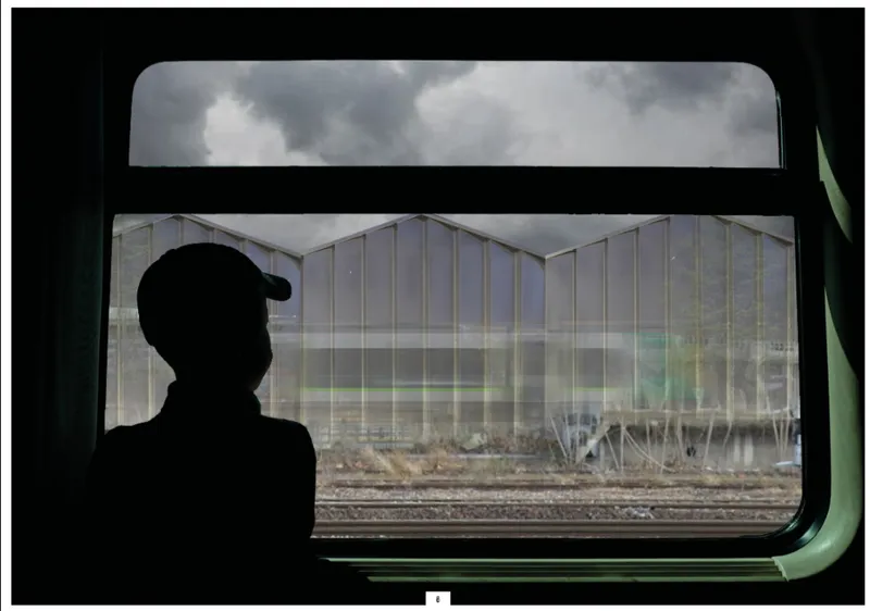View through a train window of the translucent greenhouse facade under stormy clouds