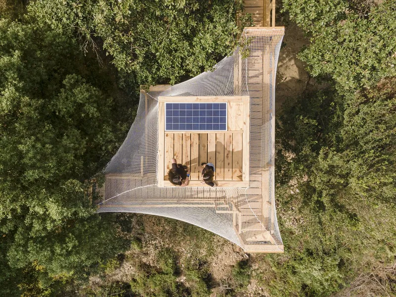 Aerial view of the timber observation platform with solar panel and mesh enclosure surrounded by trees