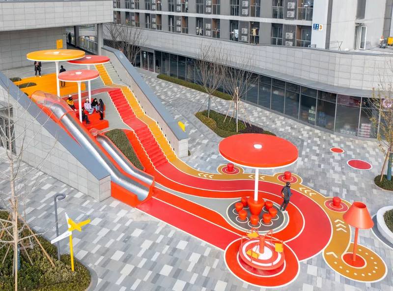 Aerial view of the courtyard playground with red and orange surfacing and circular canopies in winter
