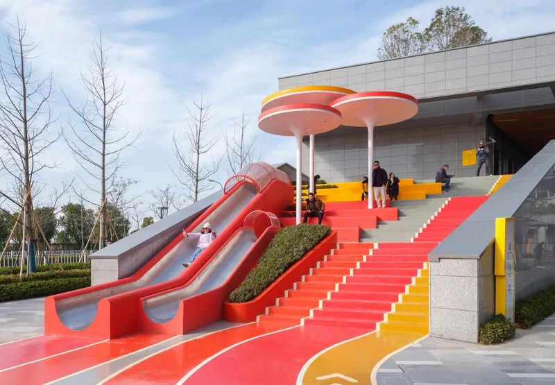 Red metal slides flanking a central staircase leading up to circular canopies on a cloudy day