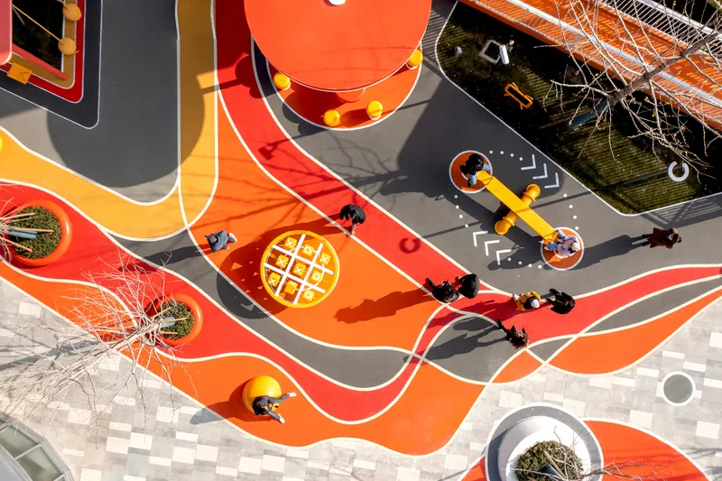 Overhead view of children crossing the wavy orange and red pathways in bright afternoon sun