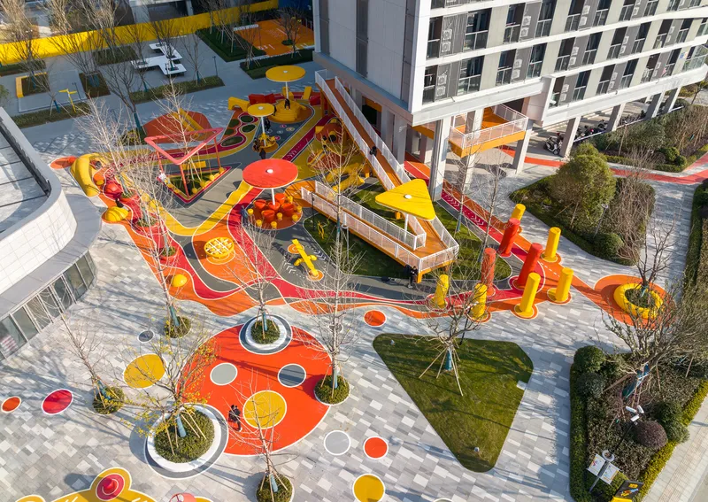 Aerial view showing the interconnected play zones with elevated walkways and young planted trees