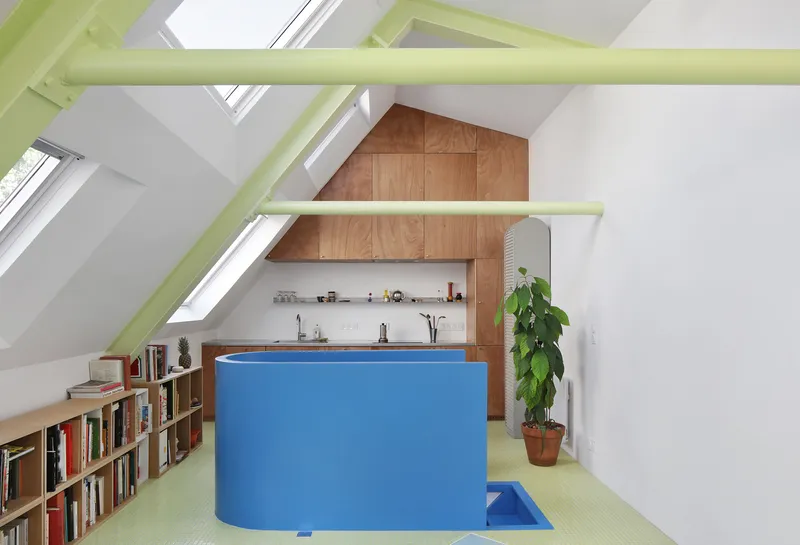 Attic kitchen with blue laminate island under lime green exposed beams and sloped skylights