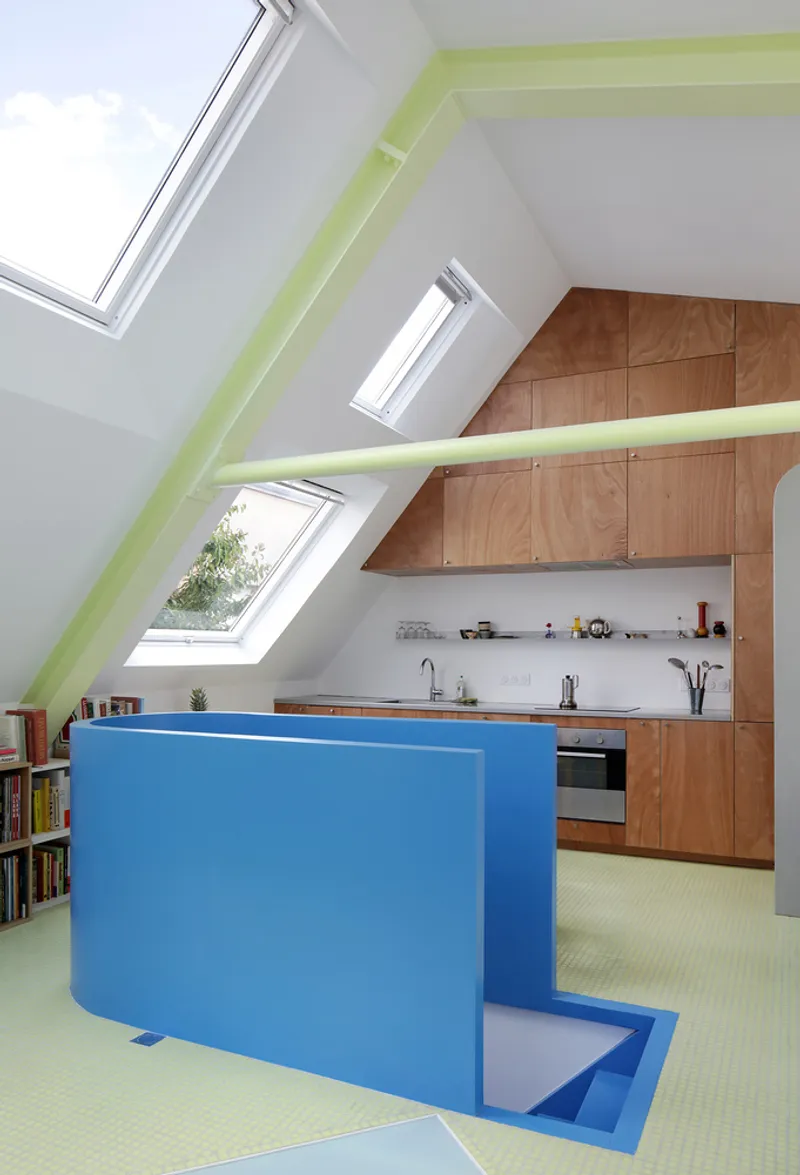 Blue stepped island with wood veneer cabinetry in an attic space with skylights framing trees