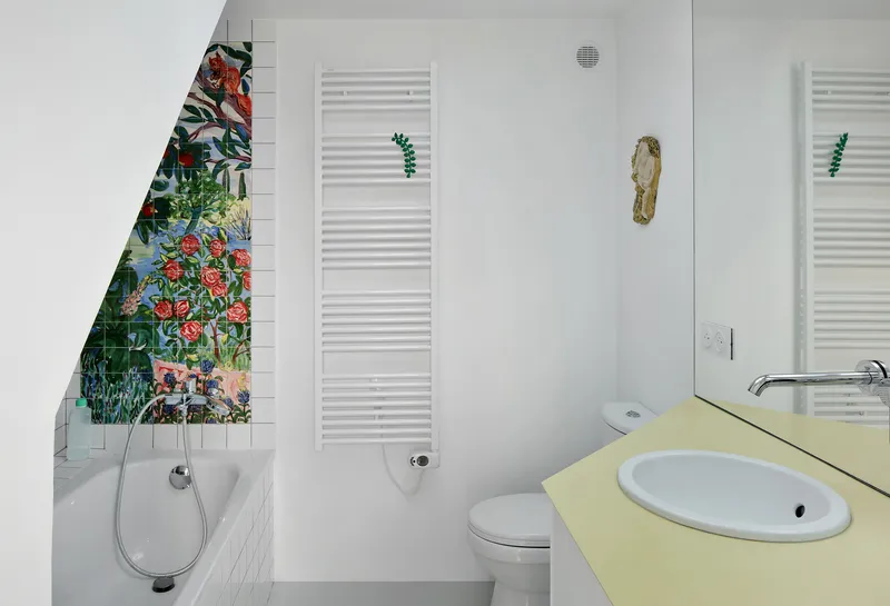 White bathroom with floral mosaic tile niche beside the tub and pale yellow vanity counter