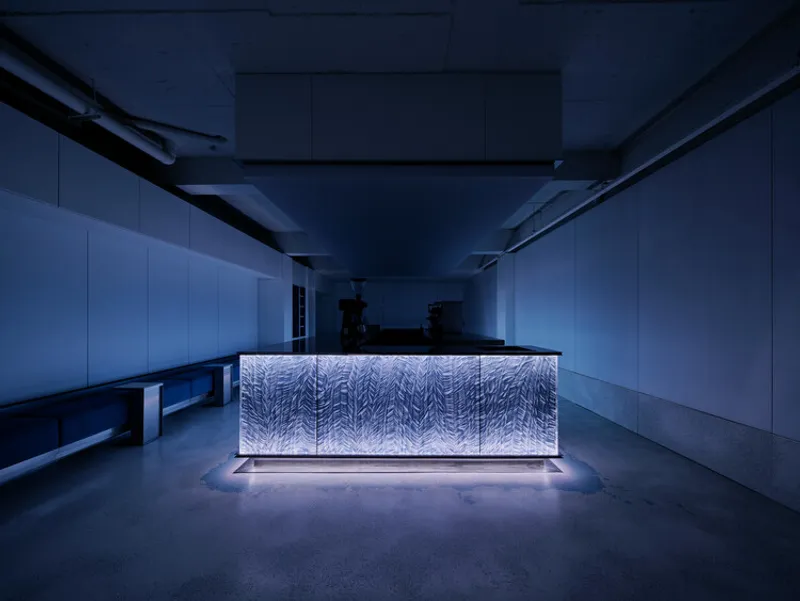 Backlit counter with textured translucent panel in a dim interior with exposed concrete floor
