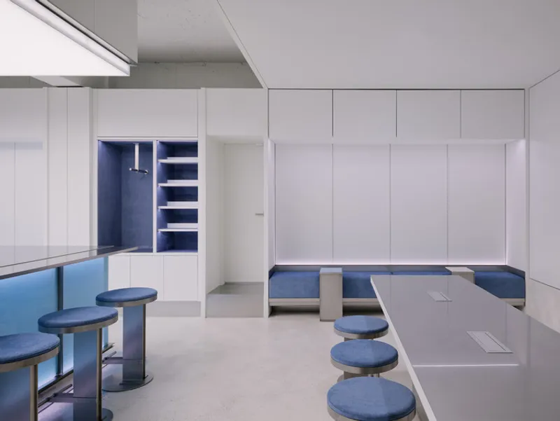 Seating area with blue upholstered stools and benches beneath white storage cabinetry