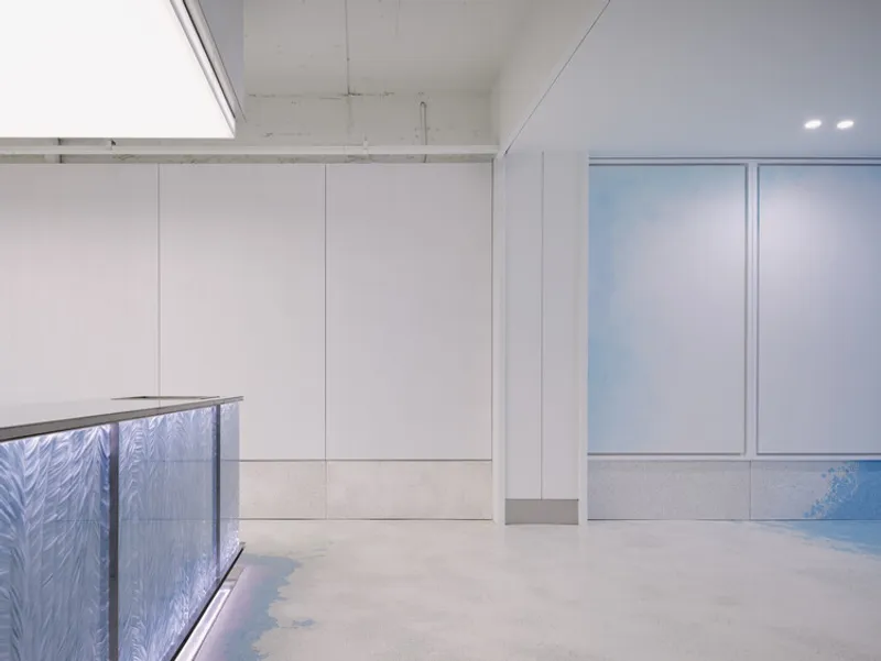 Corner of the terrazzo-clad counter beneath white wall panels and exposed concrete ceiling