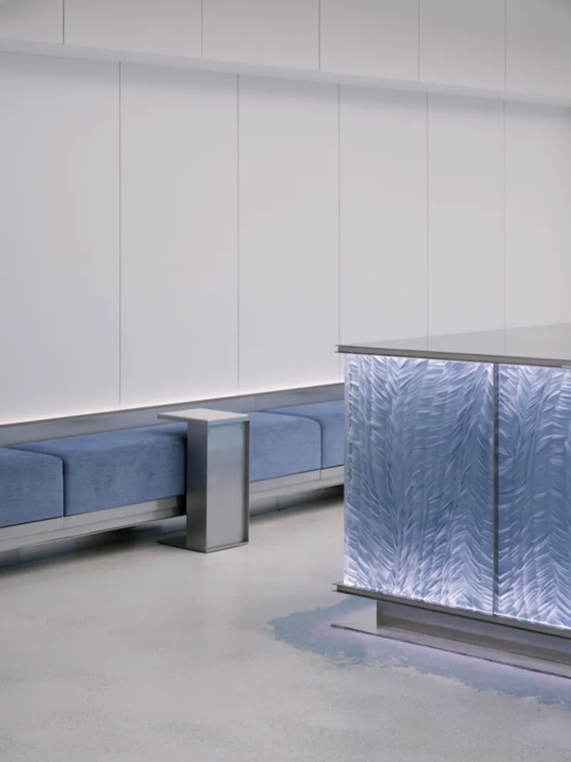 Blue fabric seating benches separated by metal dividers next to the iridescent counter base