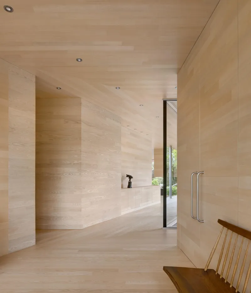 Light-toned wood-clad entry hallway with recessed lighting and glazed door to exterior garden