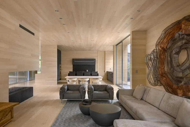 Living room with light wood ceilings and walls framing views to exterior courtyard and fireplace