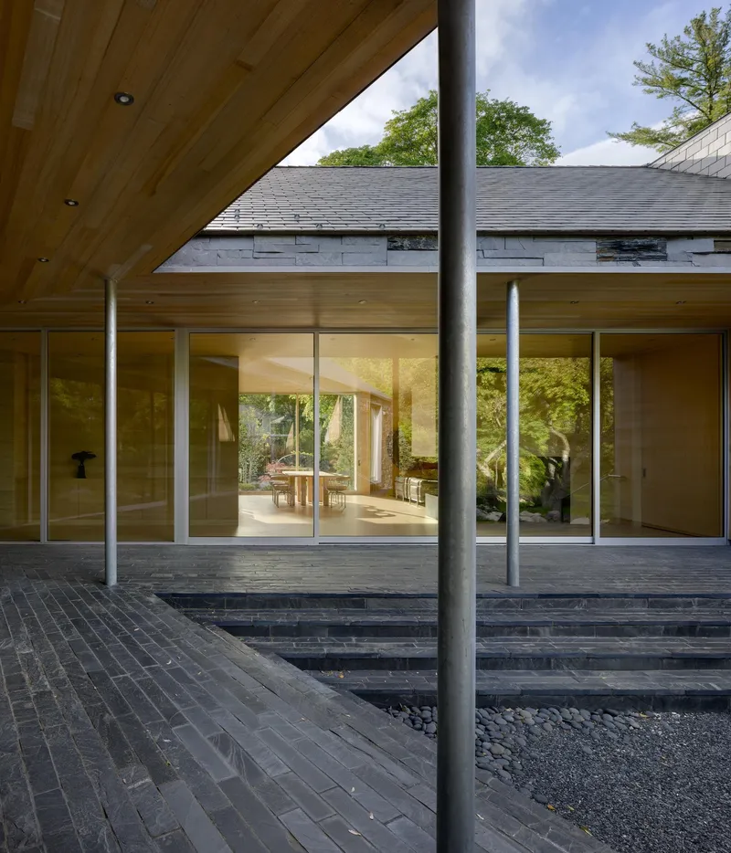 Covered terrace with timber ceiling, steel column and charcoal brick paving facing glazed living spaces