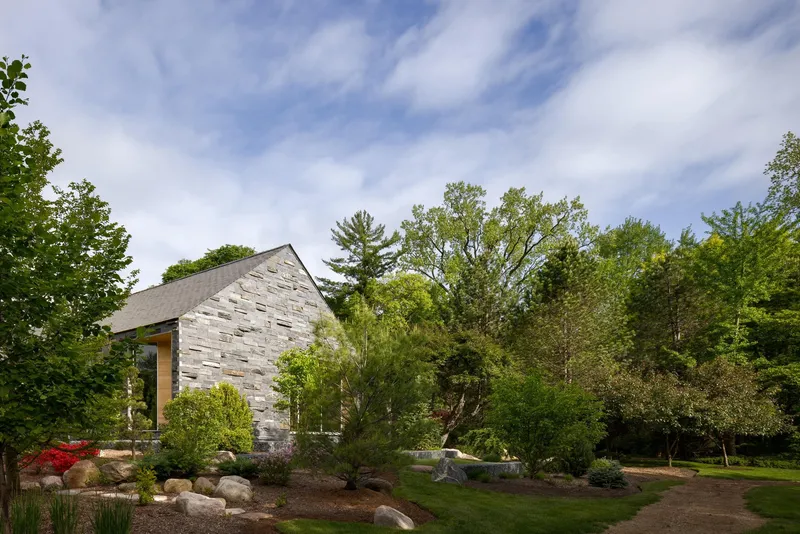Reclaimed white brick gable end rising from a landscaped garden beneath a cloudy spring sky