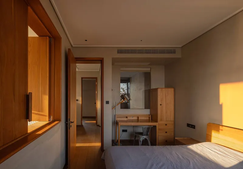 Bedroom interior showing timber-framed openings and dressing table bathed in warm late afternoon light
