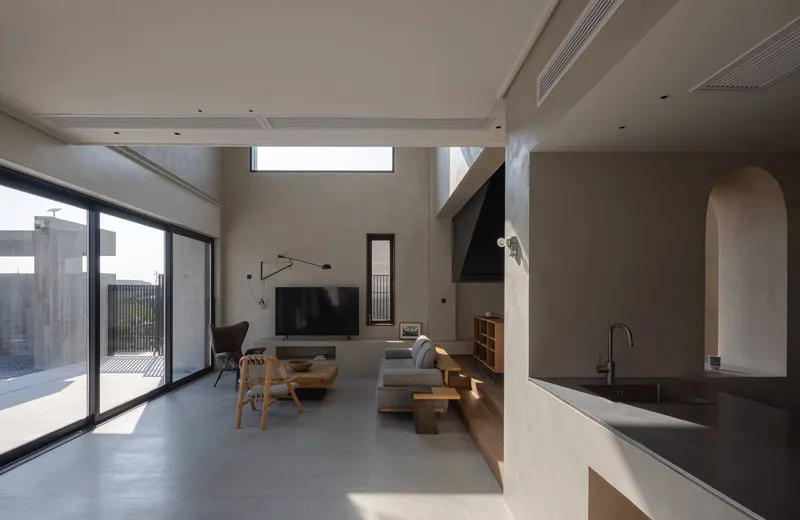 Open living area with concrete floors and clerestory windows casting daylight across kitchen island and seating