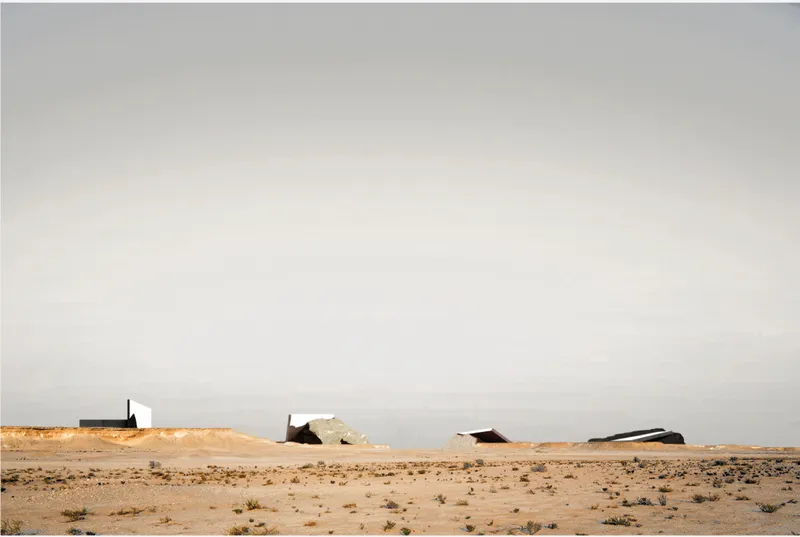 A distant view of the intervention situates the project within the vast desert, emphasizing contrast between minimal architecture and expansive landscape.