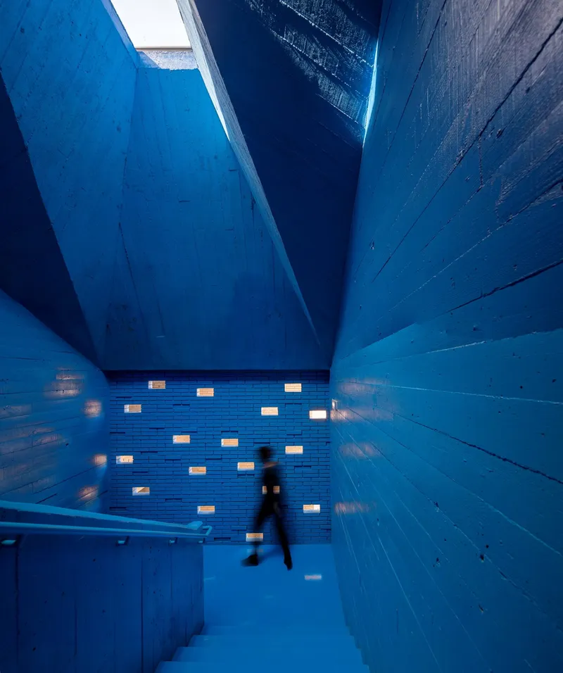 Blue-painted timber stairwell with skylight and a person descending in motion blur