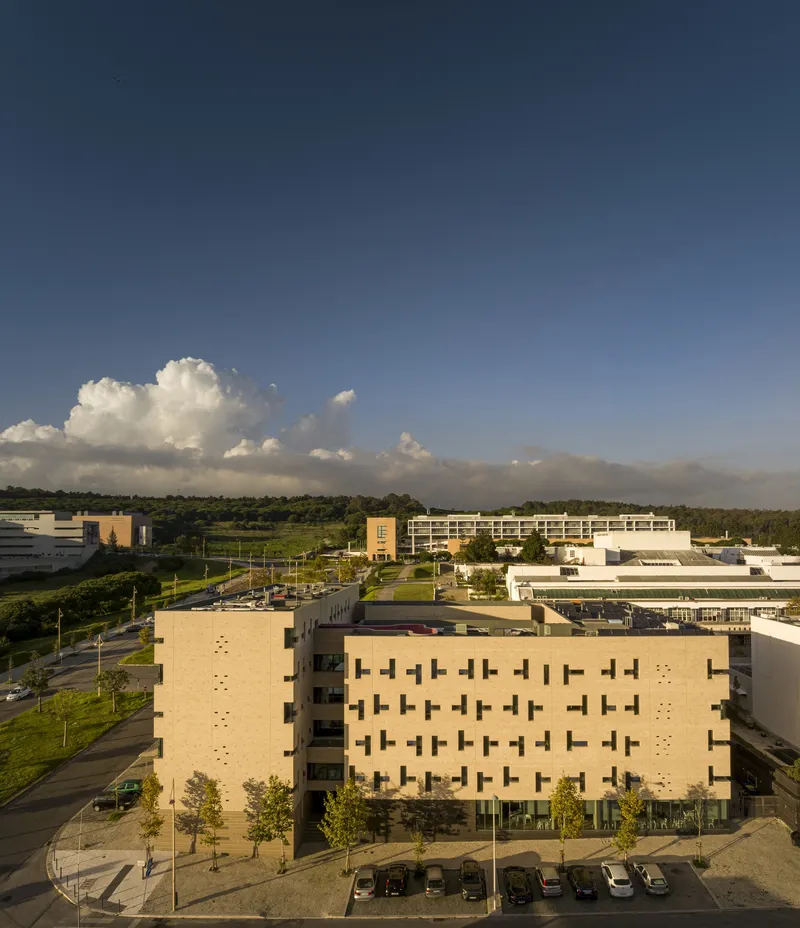 Aerial view of buff brick facade with staggered windows and parking lot at sunset