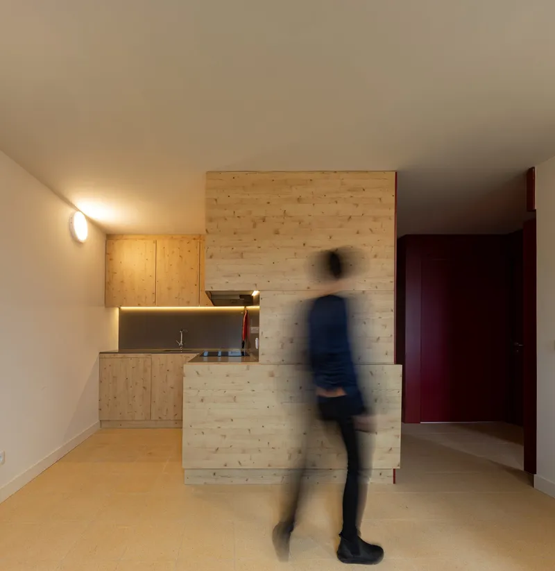 Compact kitchenette with timber cabinetry and a blurred figure in motion