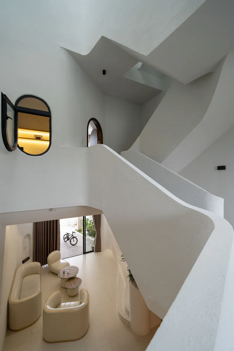 Double-height living room with spiral staircase and arched mirrors overlooking beige seating