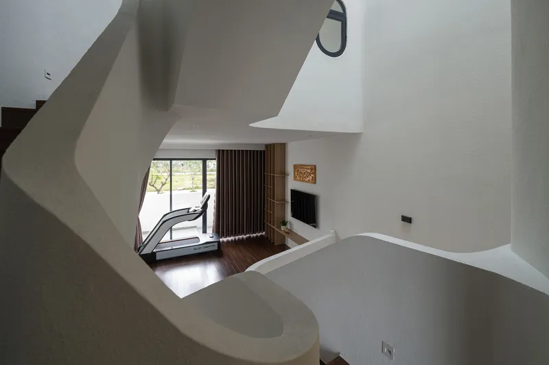 View down the curved stairwell to living space with vertical timber slat screen