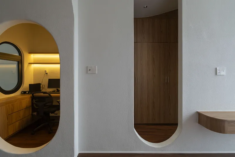 White arched openings framing timber wardrobe and study niche with yellow accent lighting