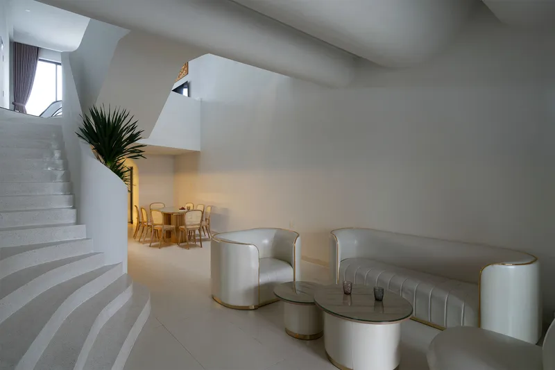 Interior view of the flowing white staircase with dining area and sculptural ceiling forms
