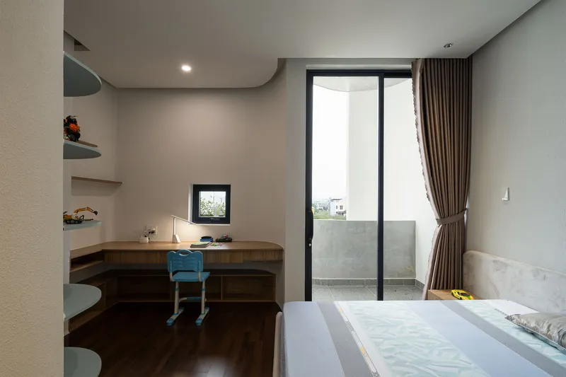 Study nook with timber desk and blue chair beside glazed door opening to balcony