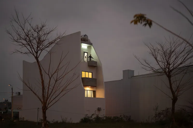 Rear elevation at night showing stacked illuminated openings between bare winter trees