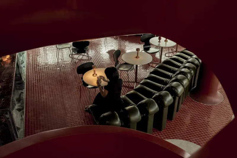 Overhead view of tiled lounge area with modular seating and a person walking between round tables