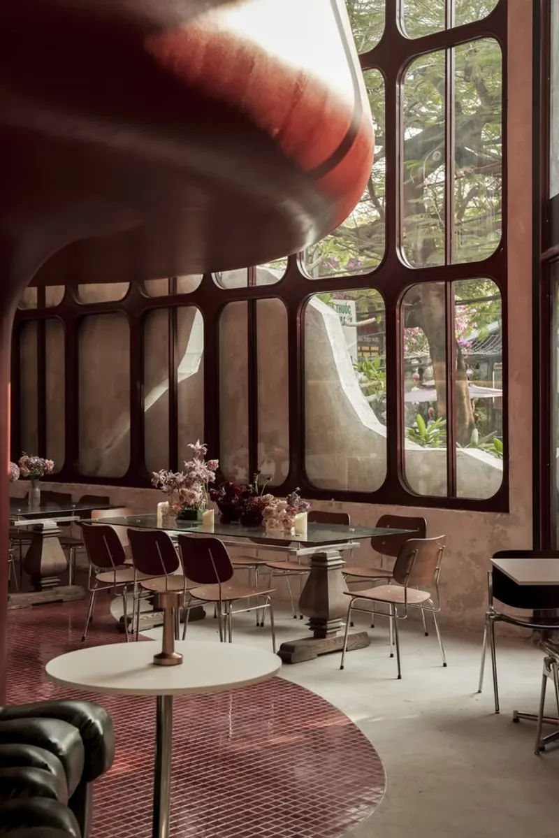 Dining area with rounded window mullions framing greenery and an inflatable sculptural element overhead