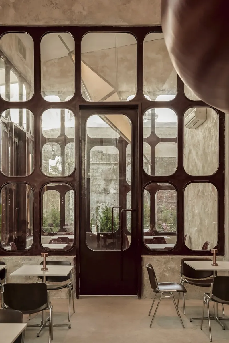 Glazed door with rounded frame mullions opening to an exterior courtyard with weathered walls