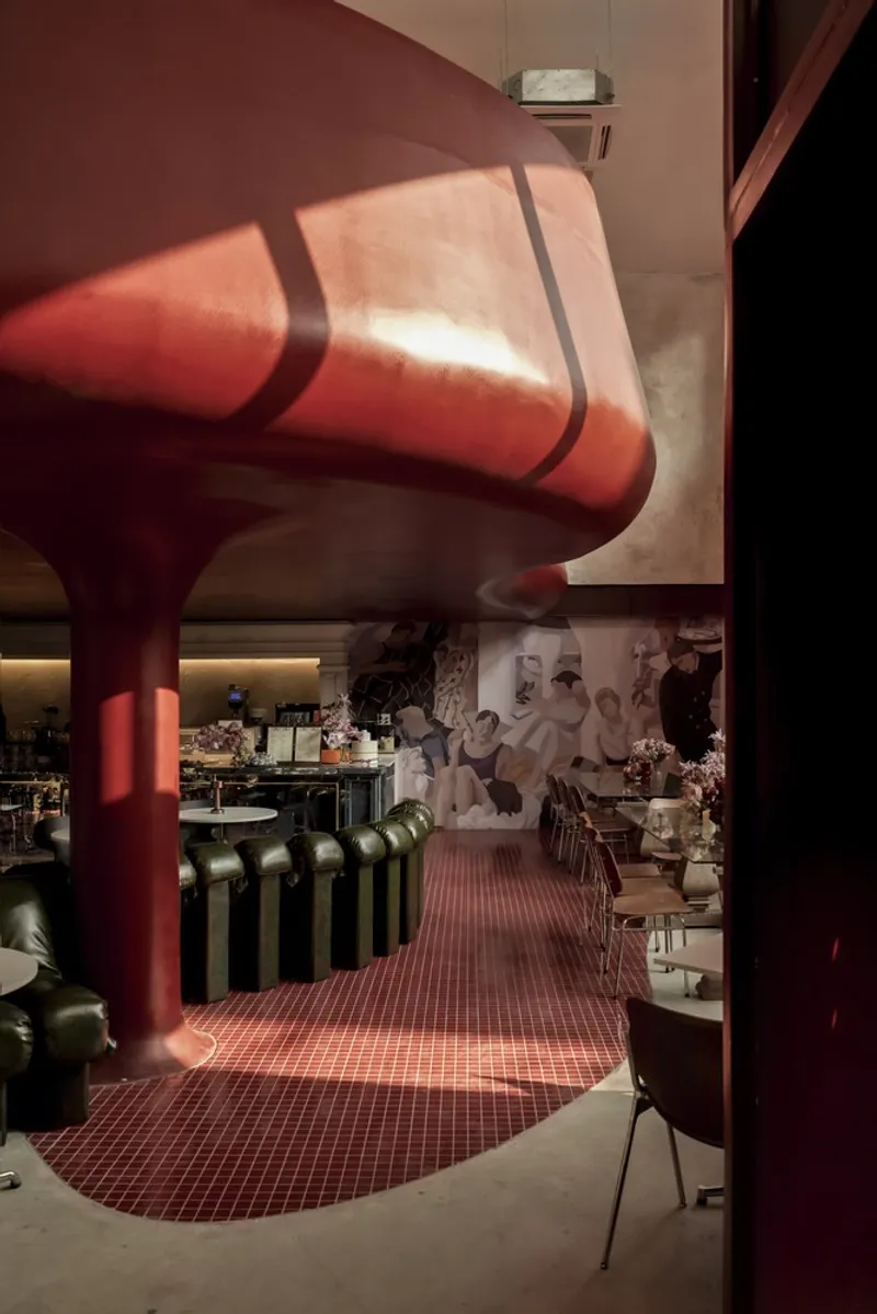 Sculptural red tubular columns supporting a low curved ceiling above a tiled dining area with ambient lighting