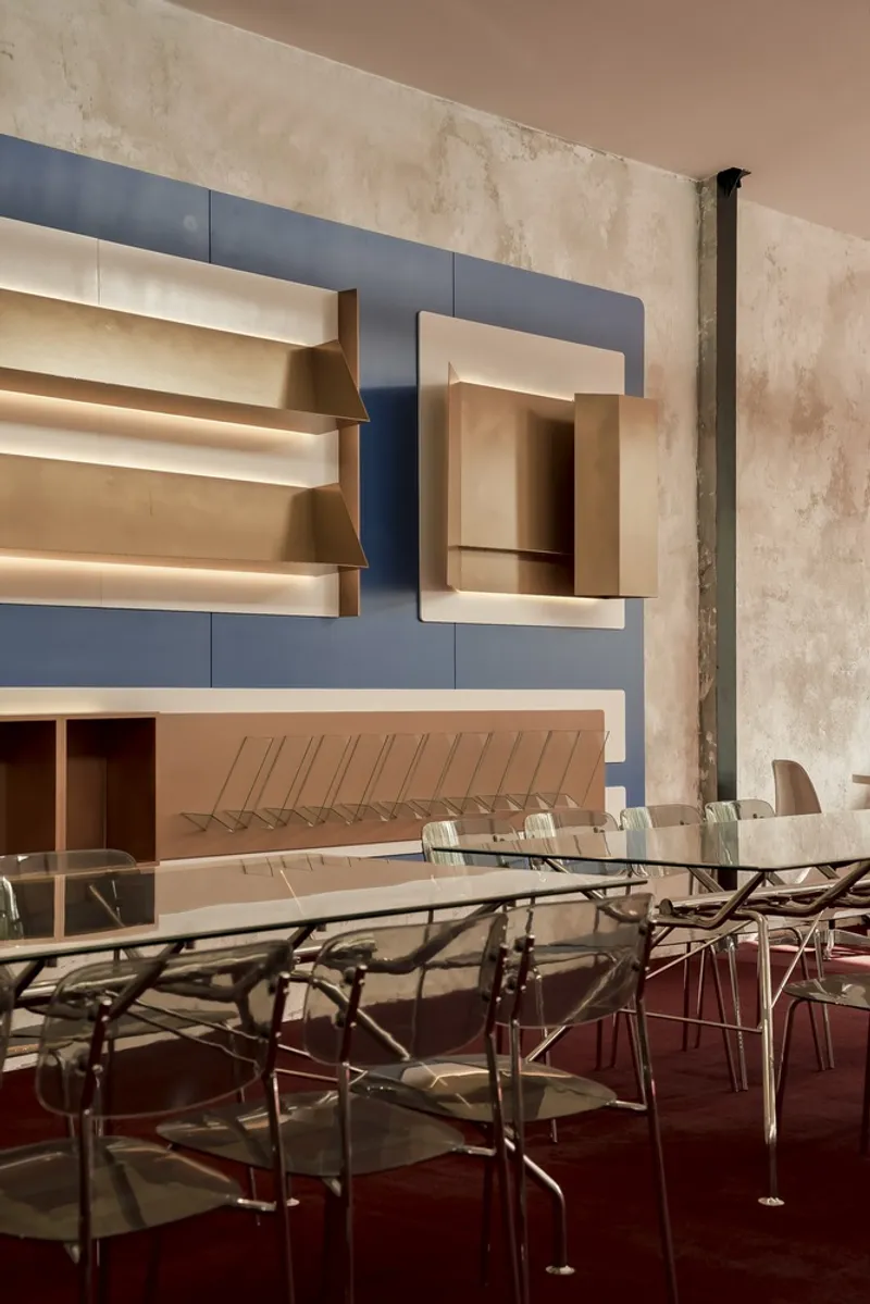 Blue paneled service wall with recessed niches and transparent dining chairs on maroon flooring