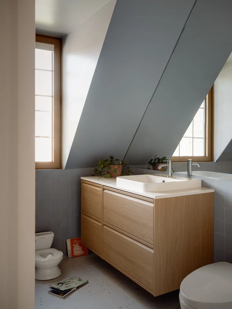 Bathroom vanity under a sloped grey ceiling with an angled skylight above