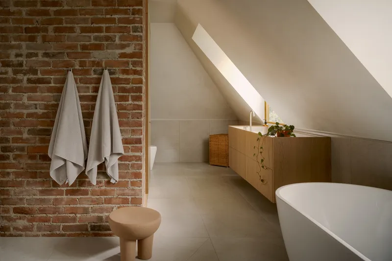 Attic bathroom with exposed brick wall and a skylight cutting across the ceiling plane