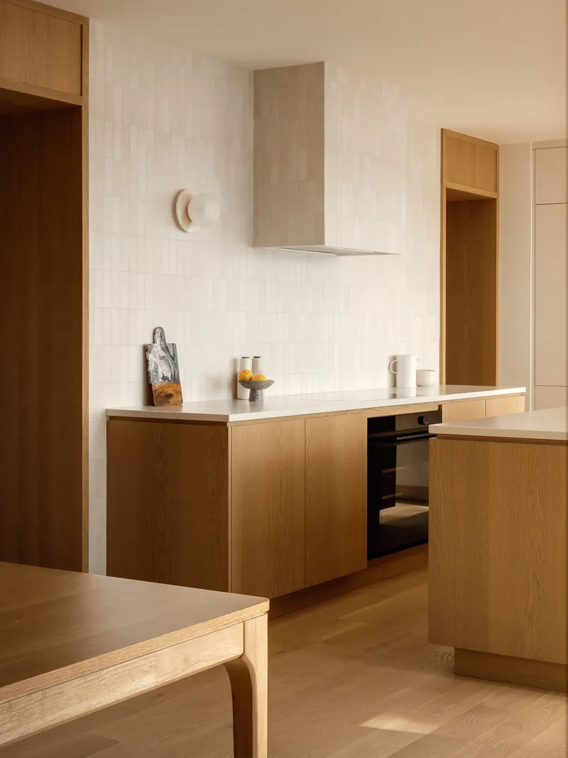 Oak kitchen counter with white vertical tile backsplash and stainless steel range hood above