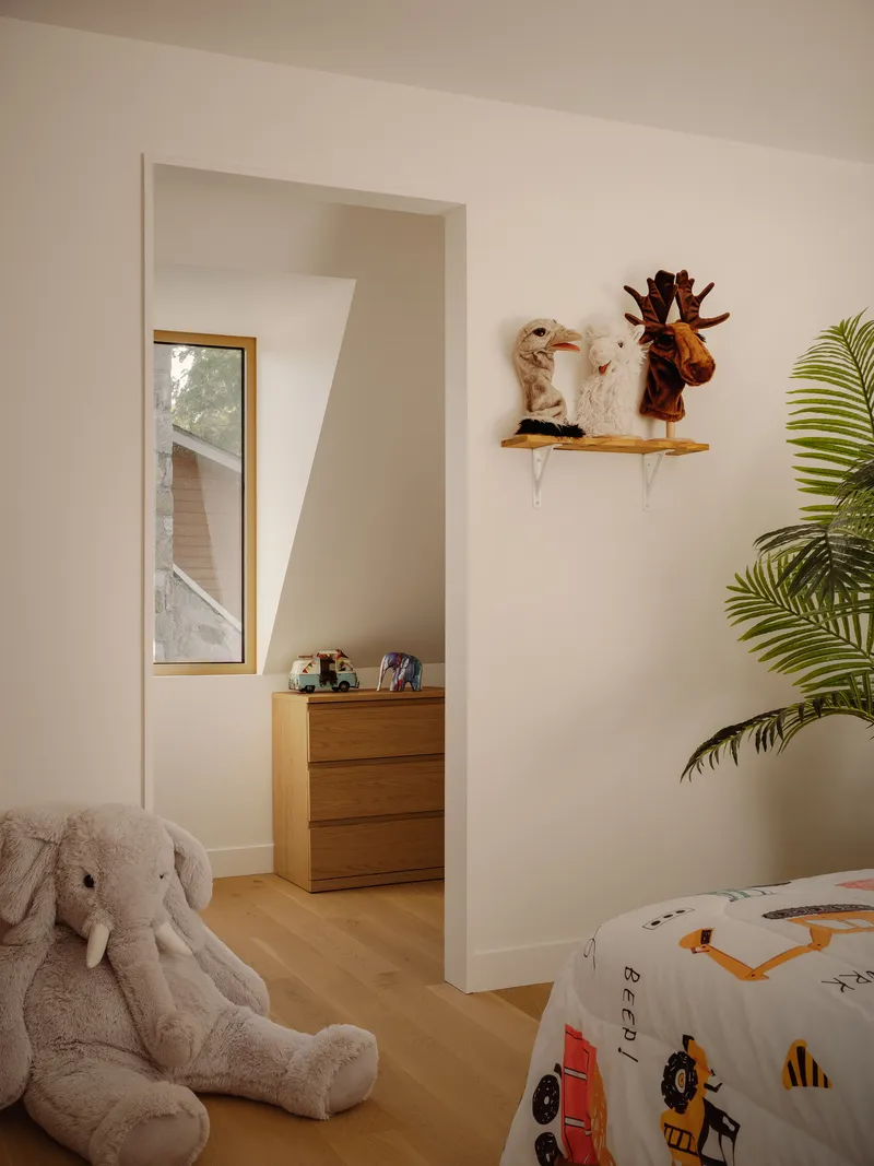 Doorway through white walls leading to an adjacent room with a narrow vertical window