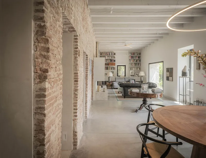 Open living space with exposed brick columns and white timber ceiling beams in natural daylight