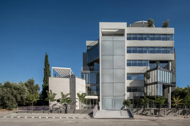 Street elevation of the white facade with recessed balconies and glass panels under a clear blue sky