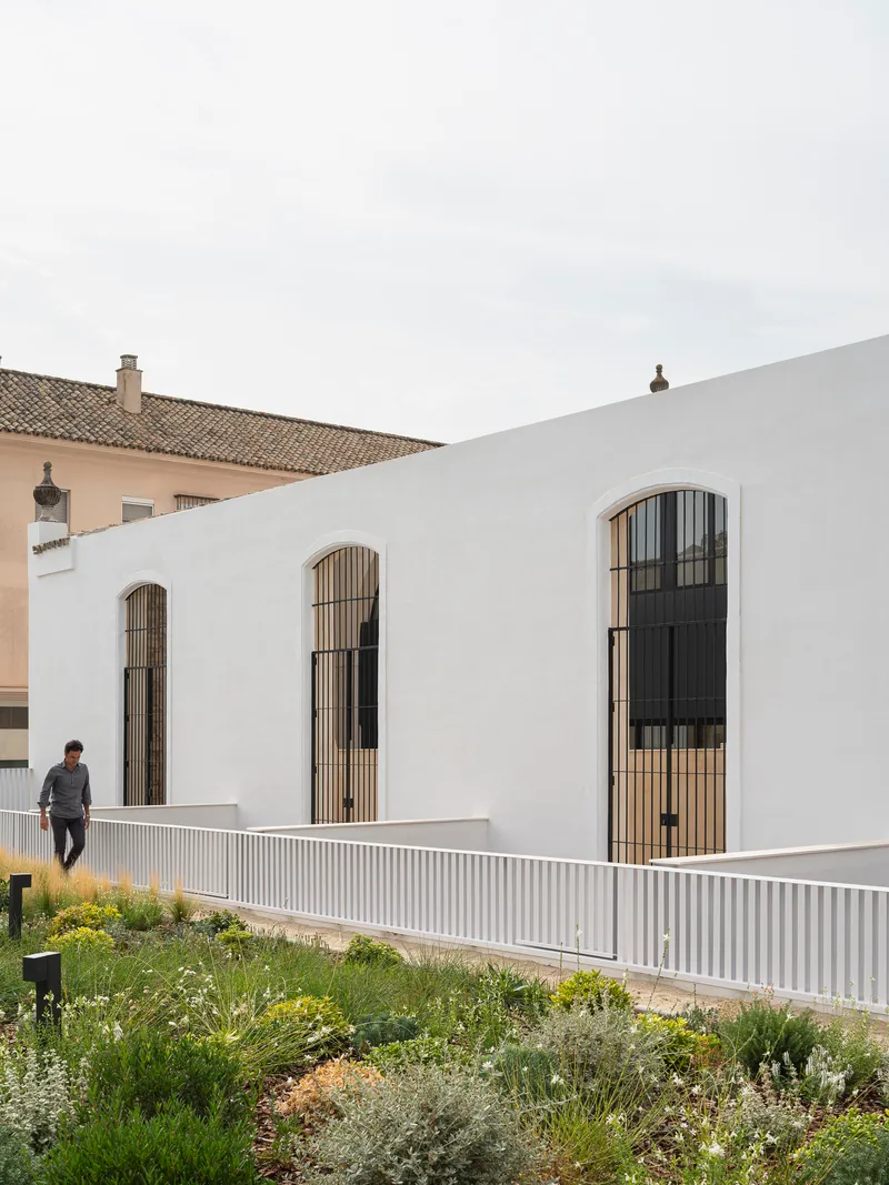 Sequence of arched windows with vertical timber screens along the long facade