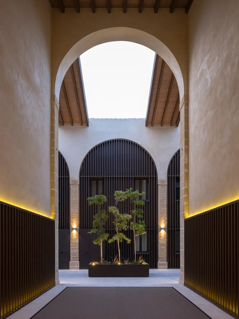 Inner courtyard framed by arches with a planted feature beyond timber screens