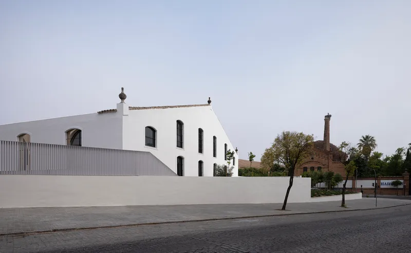 Whitewashed gable end of the historic bodega rising above the new perimeter wall