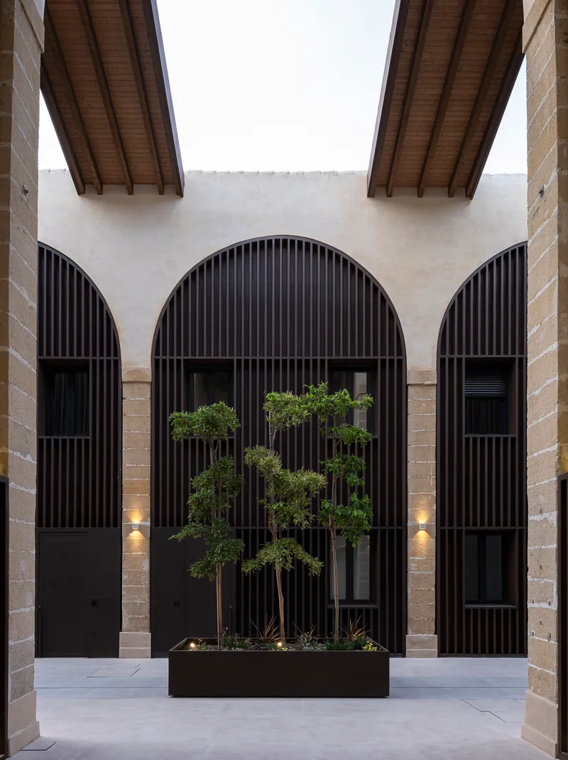 Internal courtyard with arched openings and dark vertical timber screens