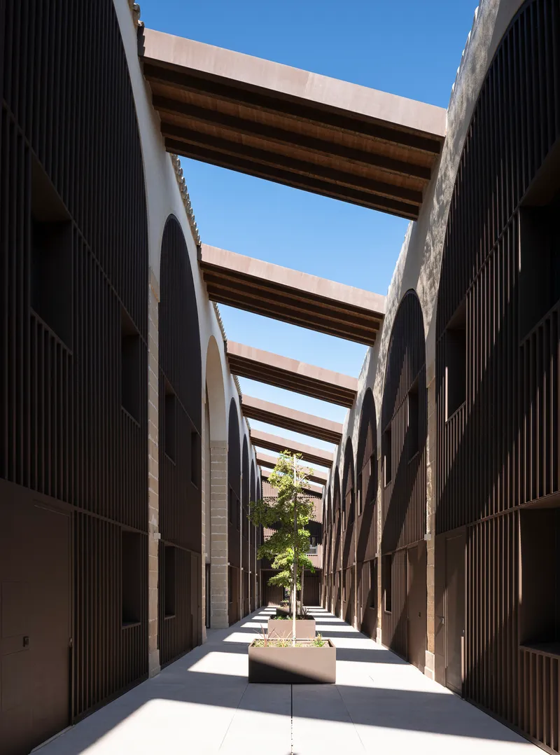 Long internal alley between residential blocks with arched timber-clad facades